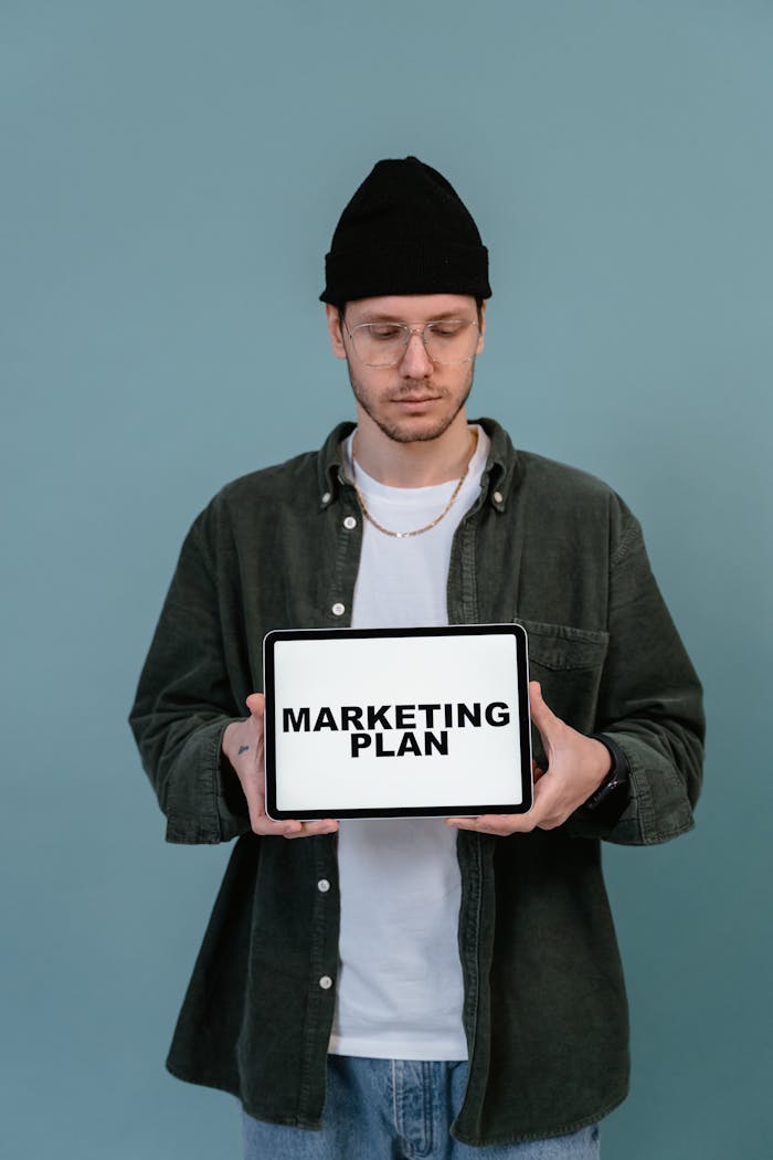 services-03 Adult wearing casual clothing holding a tablet that reads Marketing Plan.