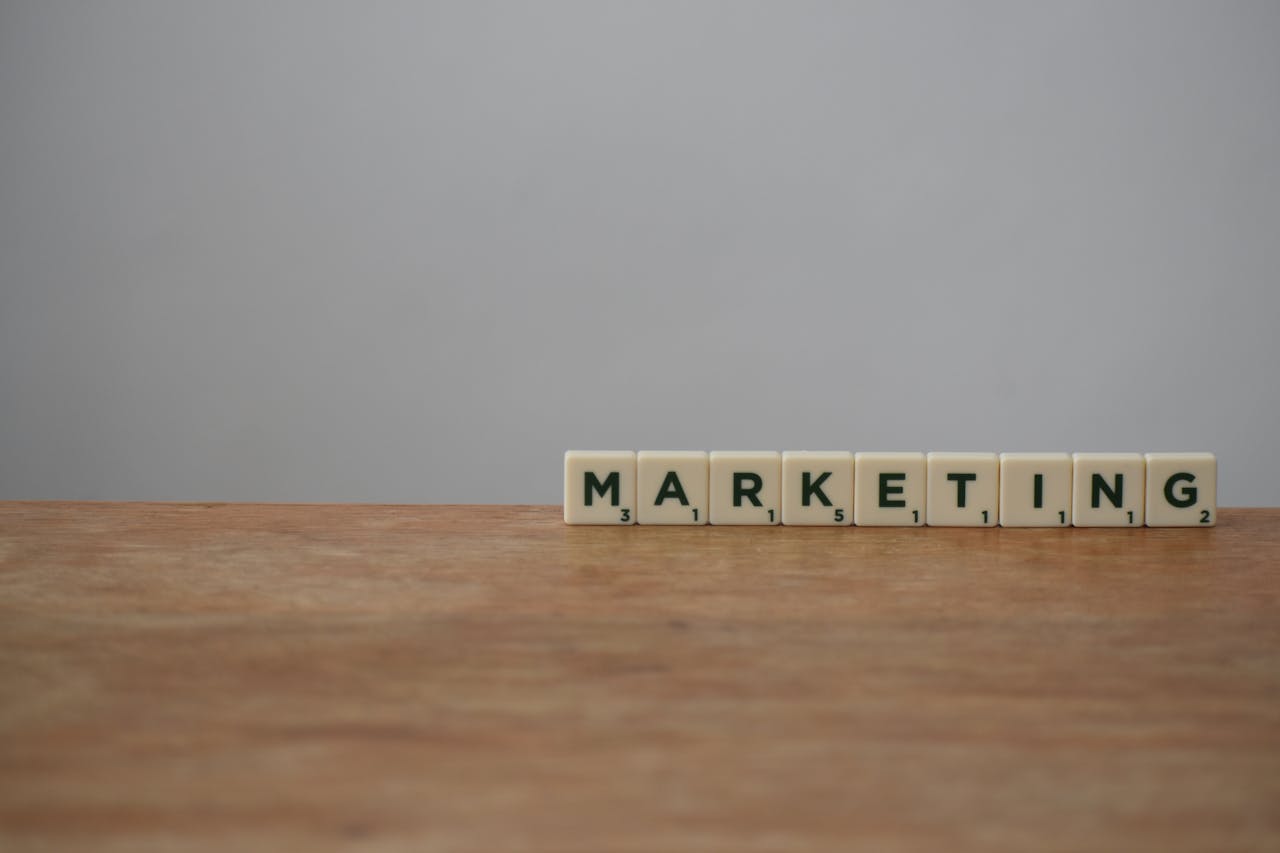 hero-img Scrabble tiles spelling MARKETING on a wooden table with a neutral background.